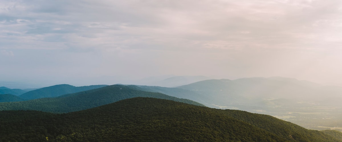 A panoramic view along the Blue Ridge Mountain range on a summer afternoon as the sun pierces through the clouds in Afton, VA.