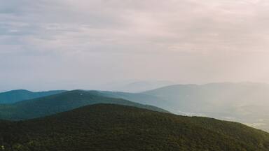 A panoramic view along the Blue Ridge Mountain range on a summer afternoon as the sun pierces through the clouds in Afton, VA.