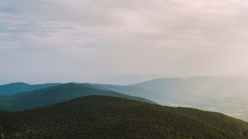 A panoramic view along the Blue Ridge Mountain range on a summer afternoon as the sun pierces through the clouds in Afton, VA.