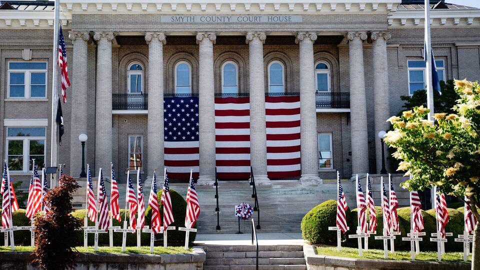 The Smyth County Court House with multiple American flags and a memorial cross.