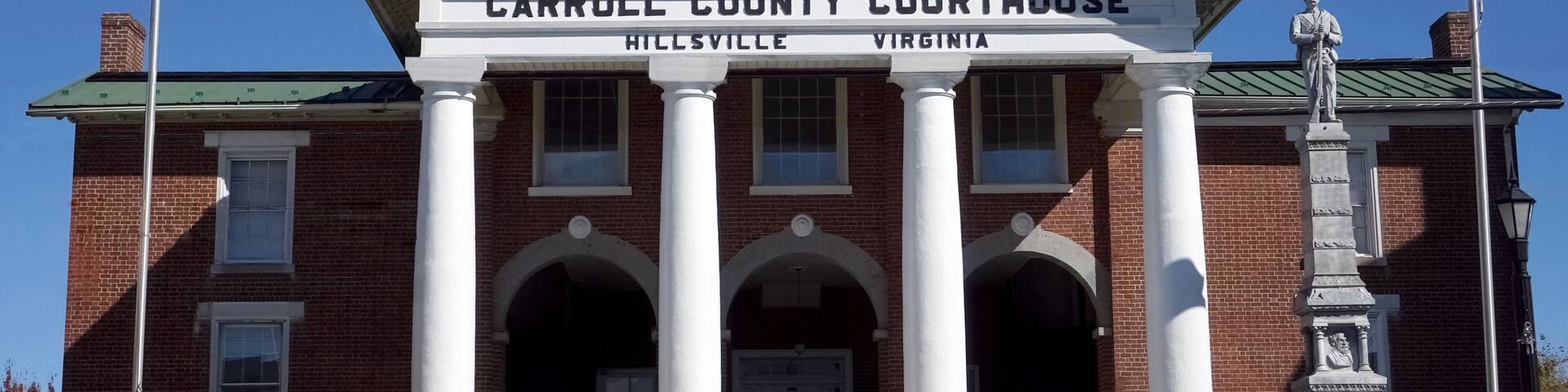 Carroll County Courthouse in Hillsville, Virginia, with a prominent entrance, white columns, and a statue.