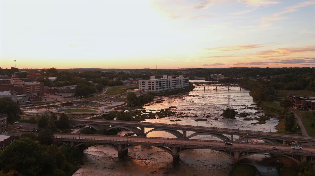Un río con un puente, un edificio y un atardecer.