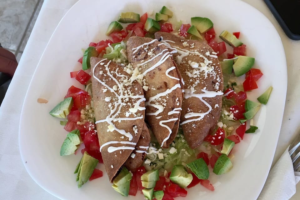 Un plato de enchiladas con ensalada de aguacate y tomate.