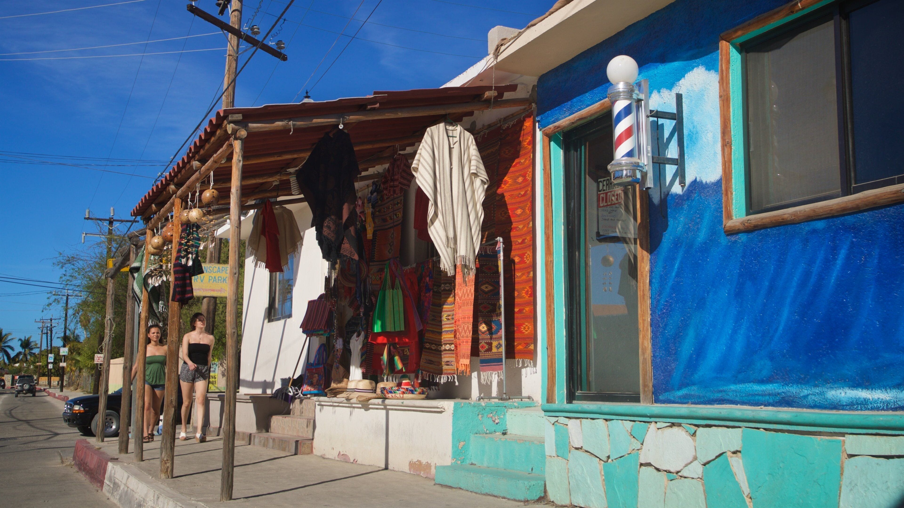 Un edificio colorido con una barbería, ropa colgando y un cartel que anuncia un parque.