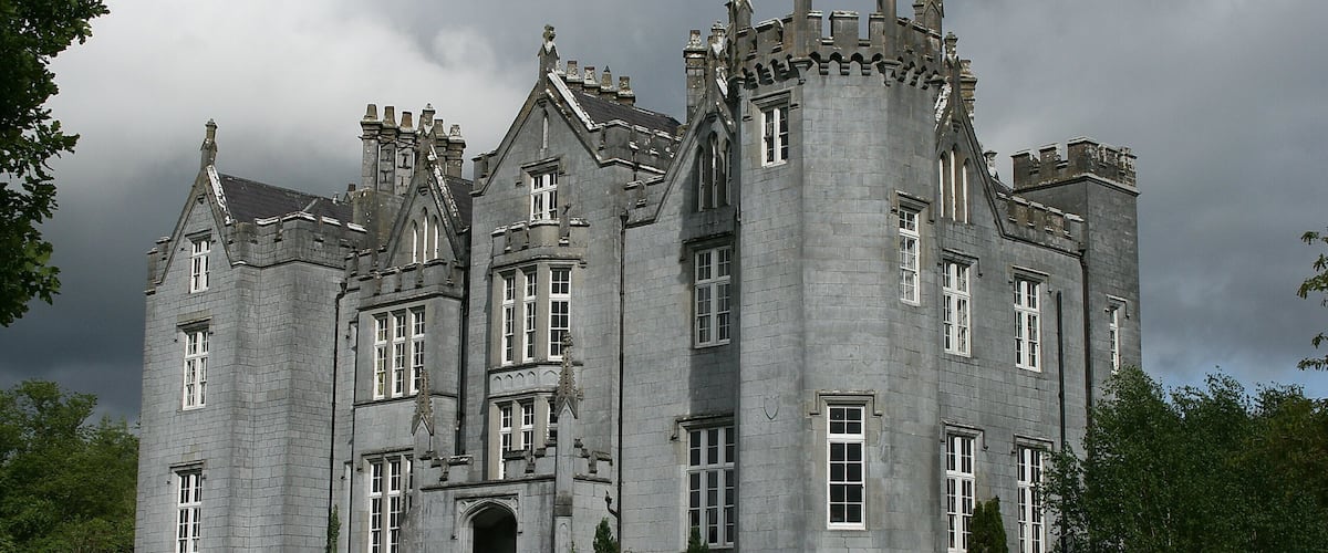 A large, historic stone building with multiple towers and arched windows.
