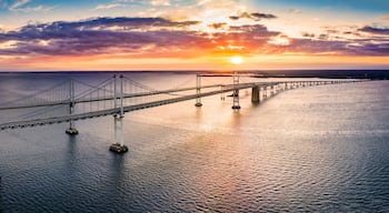 Un pont suspendu enjambant une étendue d’eau, avec un coucher de soleil en arrière-plan.