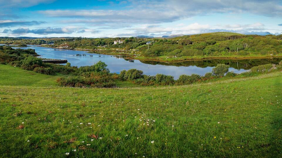 A lake surrounded by green hills and a clear sky.
