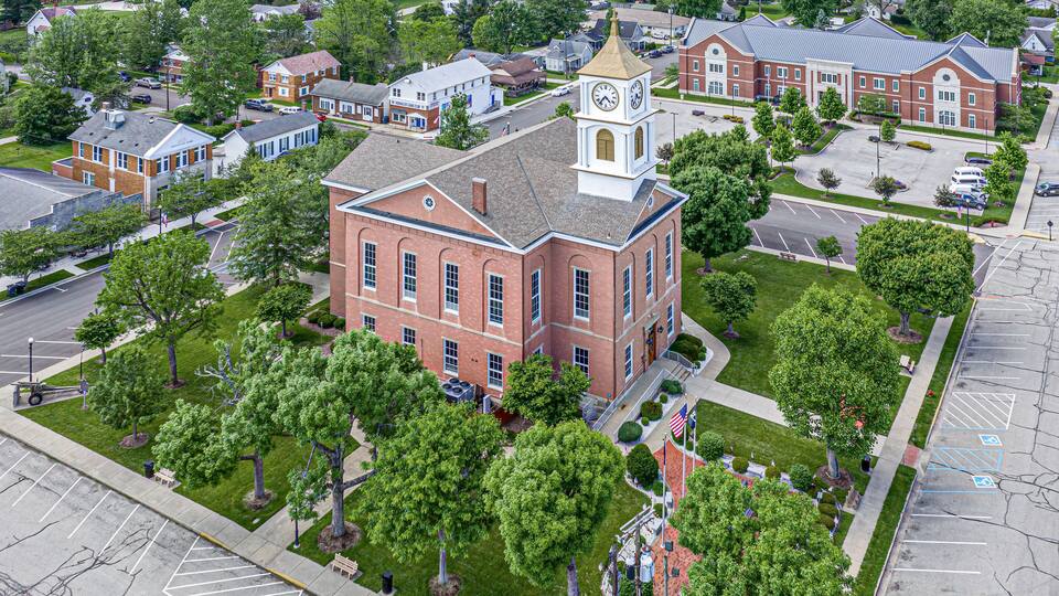 A large brick building with a clock tower, surrounded by trees and a parking lot.
