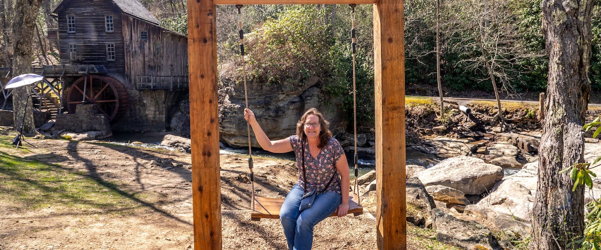 Woman on the Almost Heaven Swing in Front of the Glade Creek Grist Mill and Waterfall in West Virgina During a Sunny Spring Day