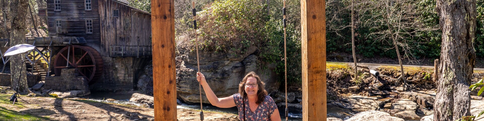 Woman on the Almost Heaven Swing in Front of the Glade Creek Grist Mill and Waterfall in West Virgina During a Sunny Spring Day