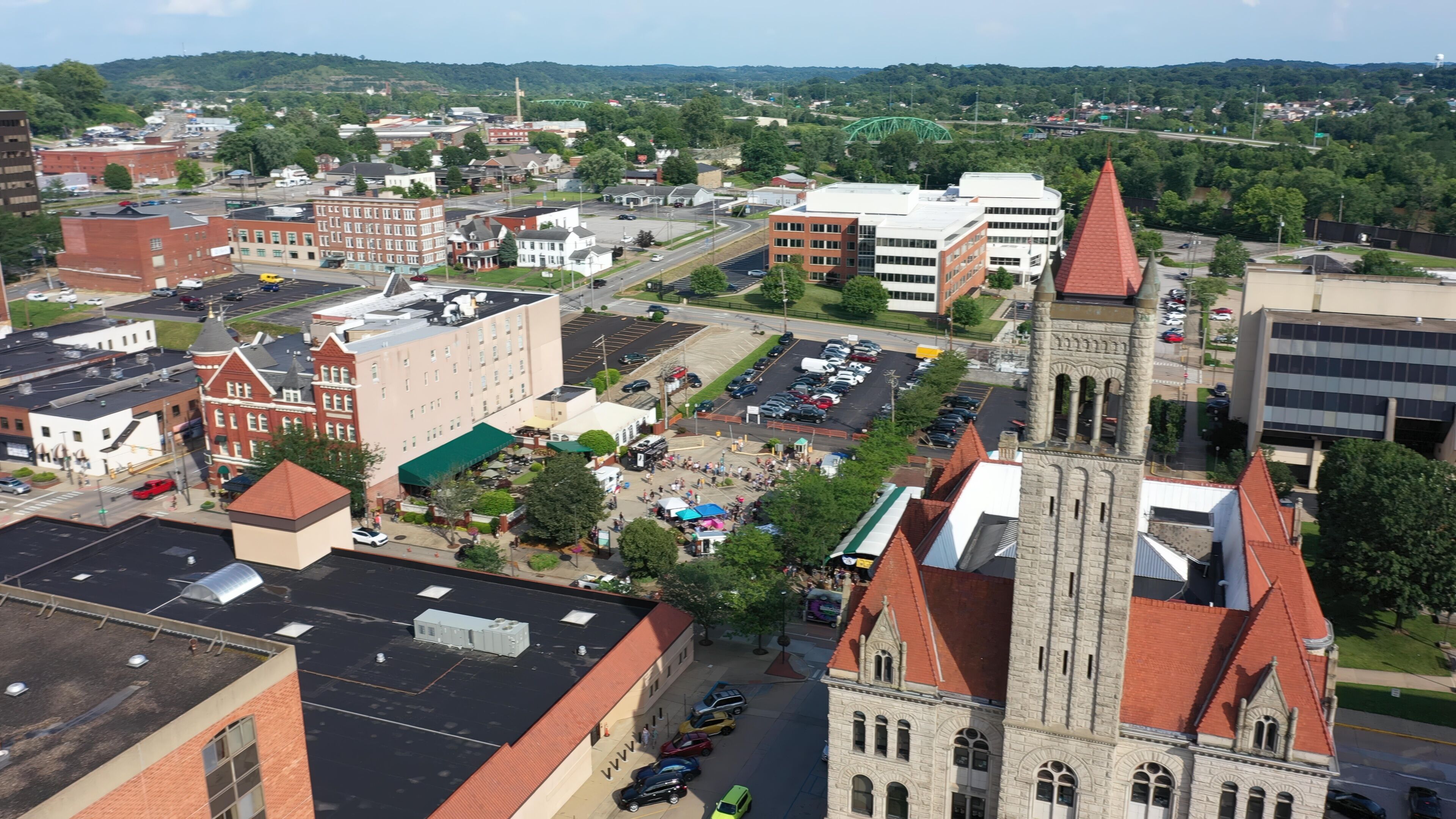 A town square with historic buildings, a church with a tall steeple, and a parking lot.