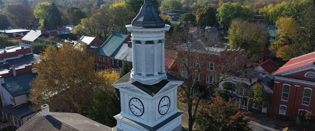Une tour de l’horloge à deux cadrans, entourée d’immeubles et d’arbres.