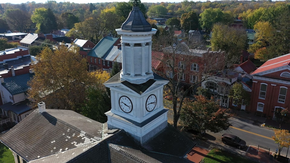 A clock tower with two faces, surrounded by buildings and trees.