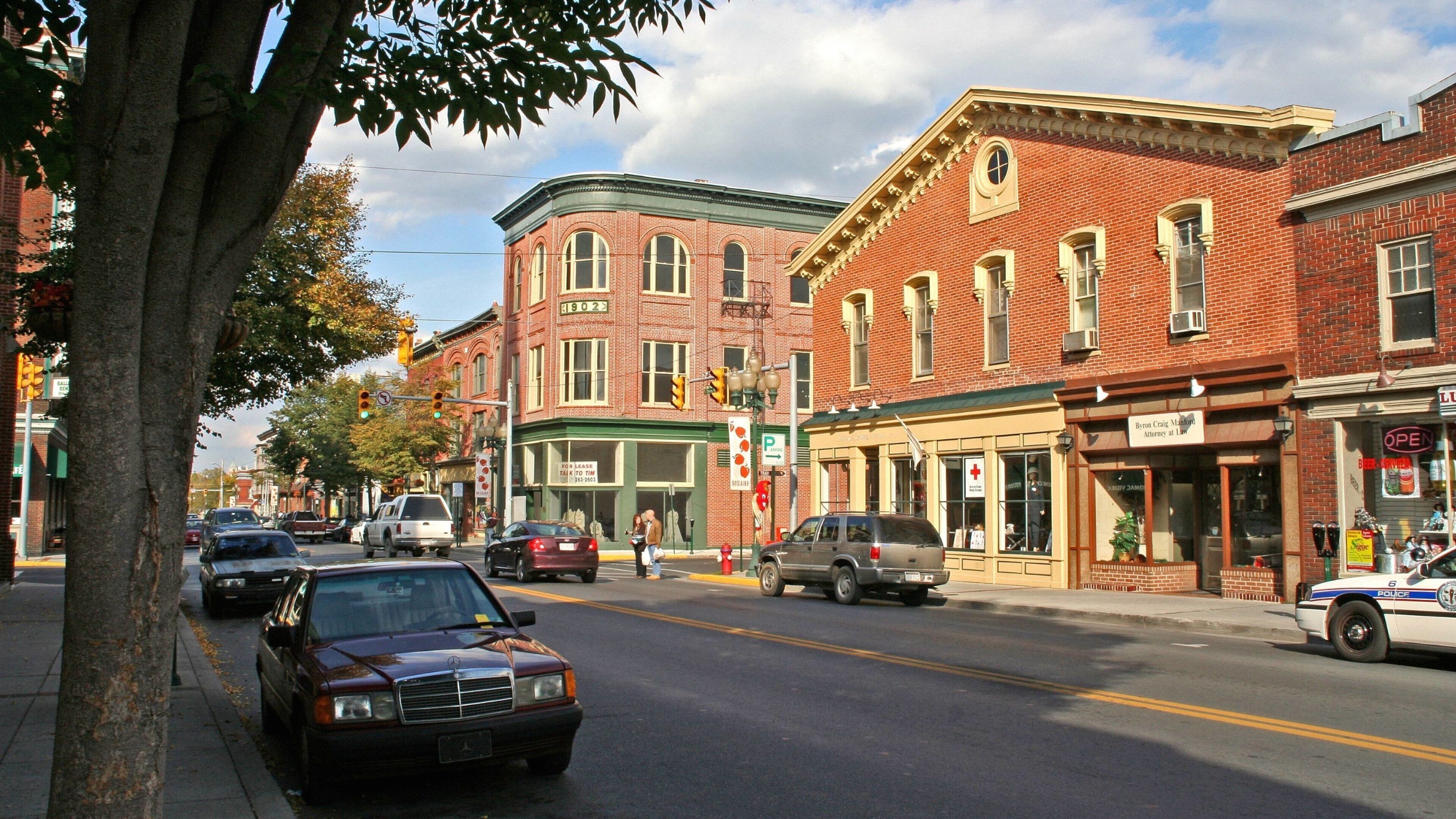 A street lined with brick buildings, including a pharmacy and a restaurant.