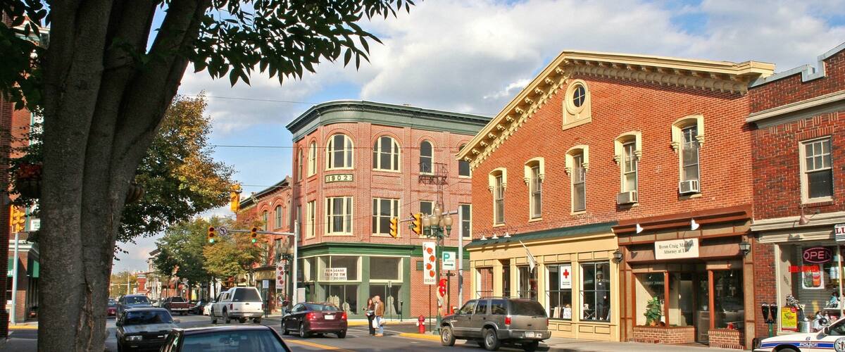A street lined with brick buildings, including a pharmacy and a restaurant.
