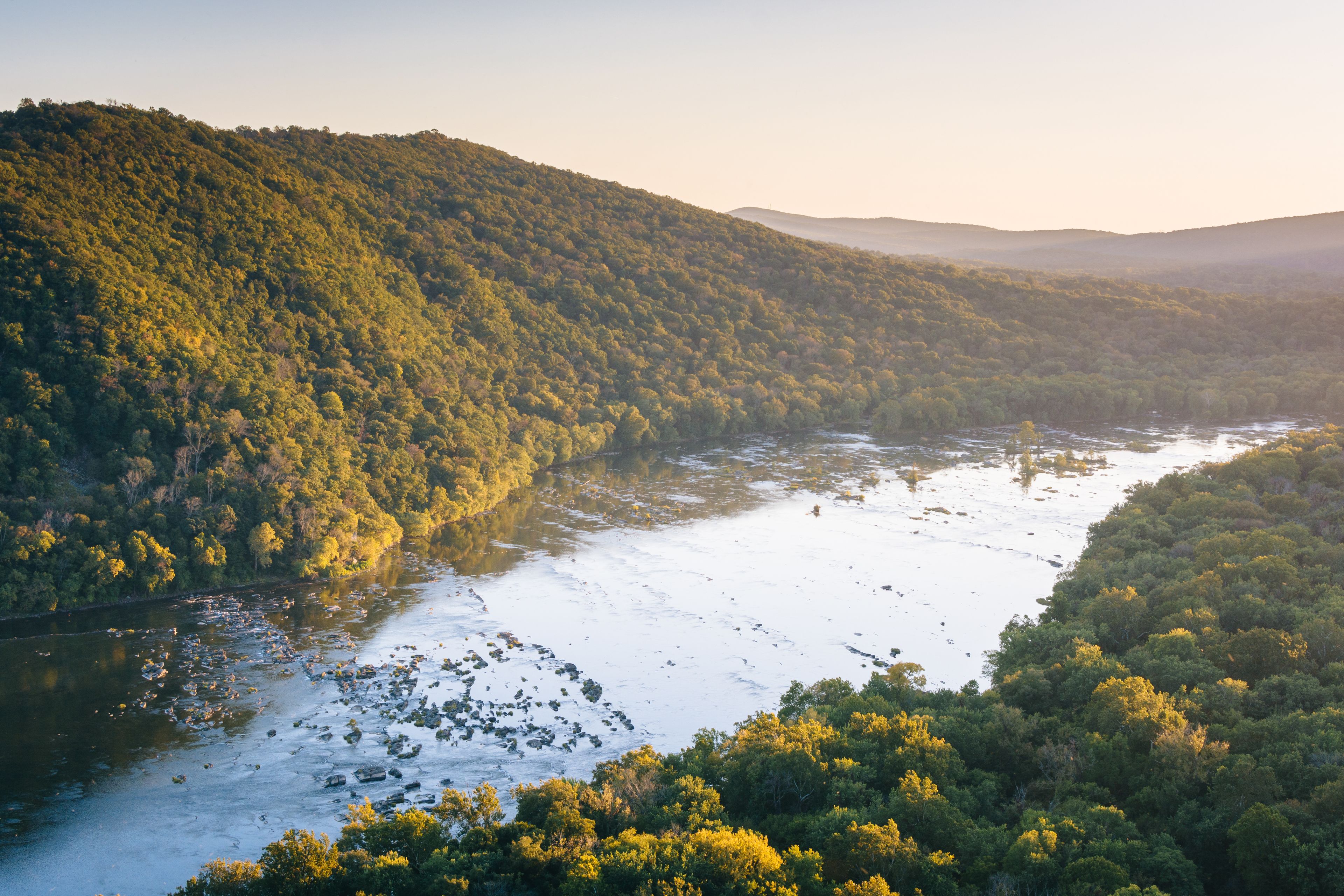 A river winding through a densely forested valley with hills on either side.