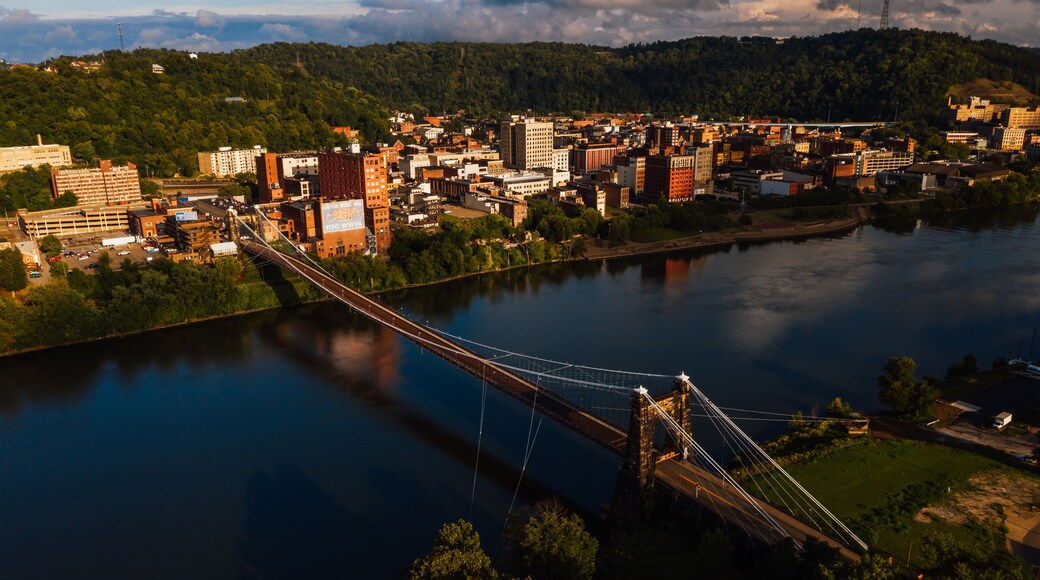 This is an aerial view of the historic Wheeling Suspension Bridge that carries the National Road over the still blue waters of the Ohio River in Wheeling, West Virginia.
