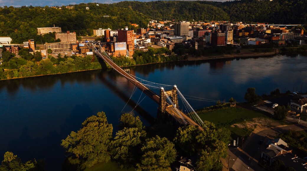 This is an aerial view of the historic Wheeling Suspension Bridge that carries the National Road over the still blue waters of the Ohio River in Wheeling, West Virginia.