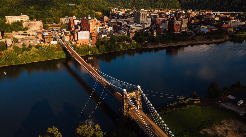This is an aerial view of the historic Wheeling Suspension Bridge that carries the National Road over the still blue waters of the Ohio River in Wheeling, West Virginia.
