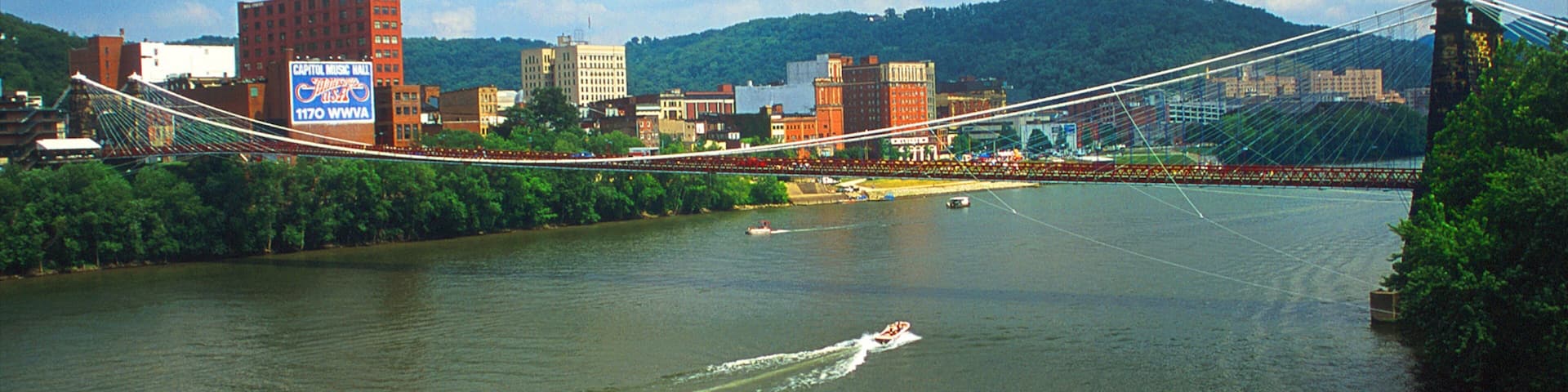 Wheeling das einen Fluss oder Bach, HĂ€ngebrĂŒcke oder Baumkronenpfad und Stadt