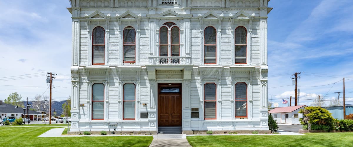 A white historic building with a central tower, large windows, and a sign reading "Old House."