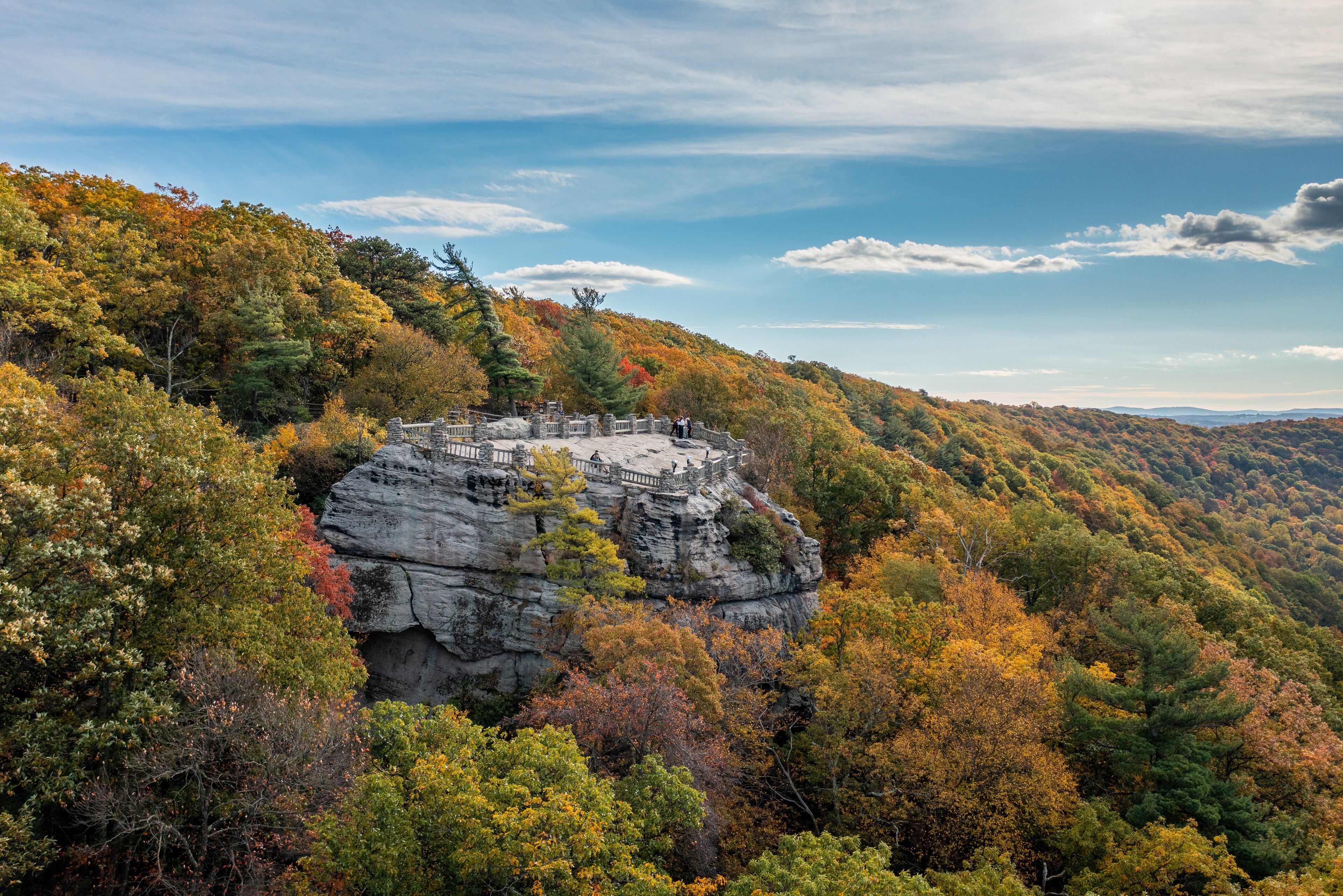 A rocky cliff with a viewing platform surrounded by autumn foliage.