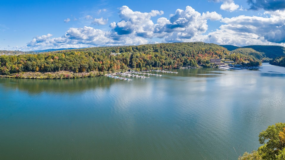 A lake with a bridge, surrounded by hills and autumn-colored trees.