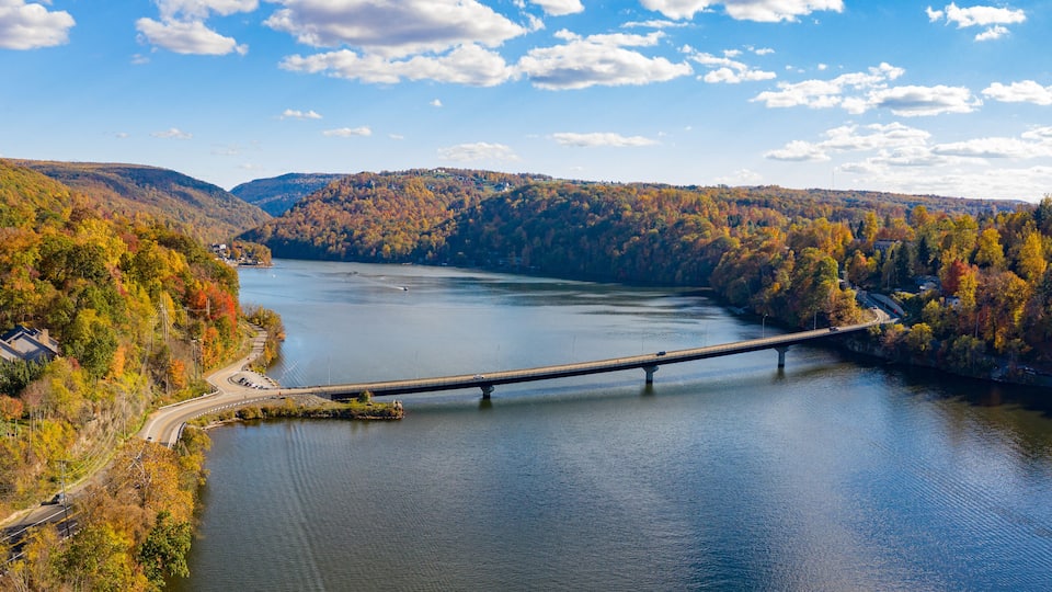 A river with a bridge, surrounded by autumn-colored trees and hills.