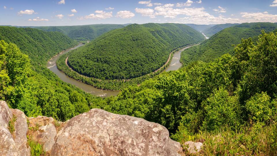 A river winding through a lush valley with dense green forests and rolling hills.
