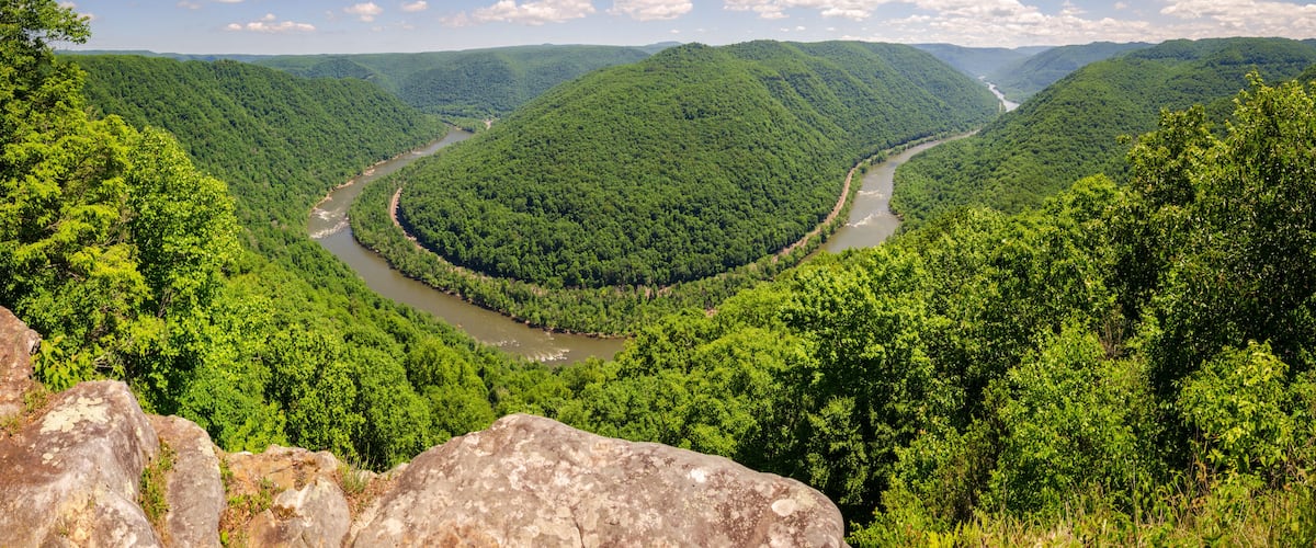 A river winding through a lush valley with dense green forests and rolling hills.
