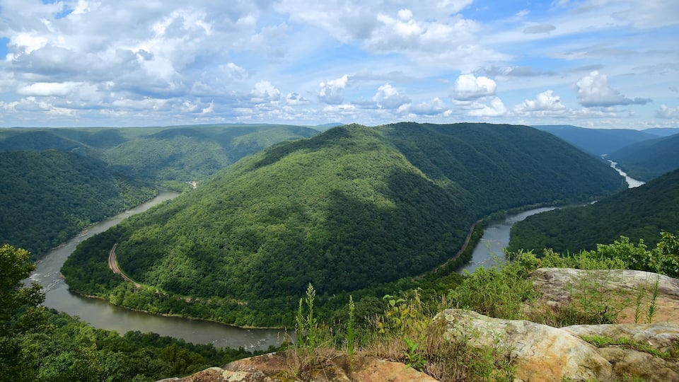 A river winding through lush green hills under a partly cloudy sky.