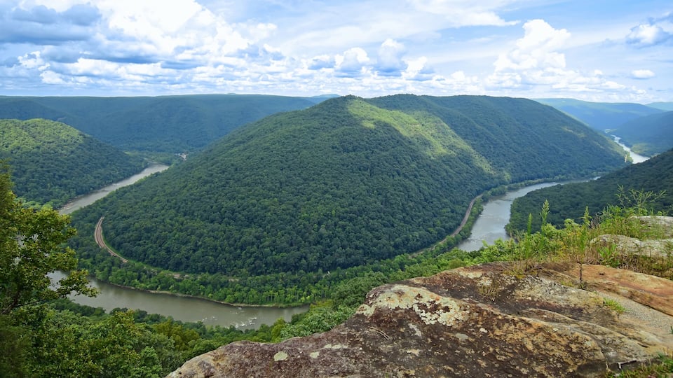 A river winding through a densely forested valley with mountains in the background.
