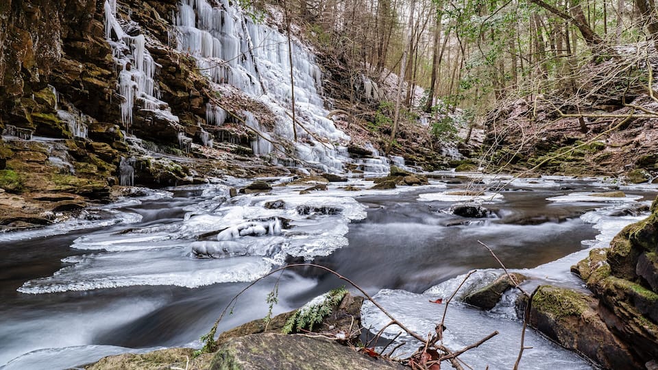 A river with ice formations and a forested area.