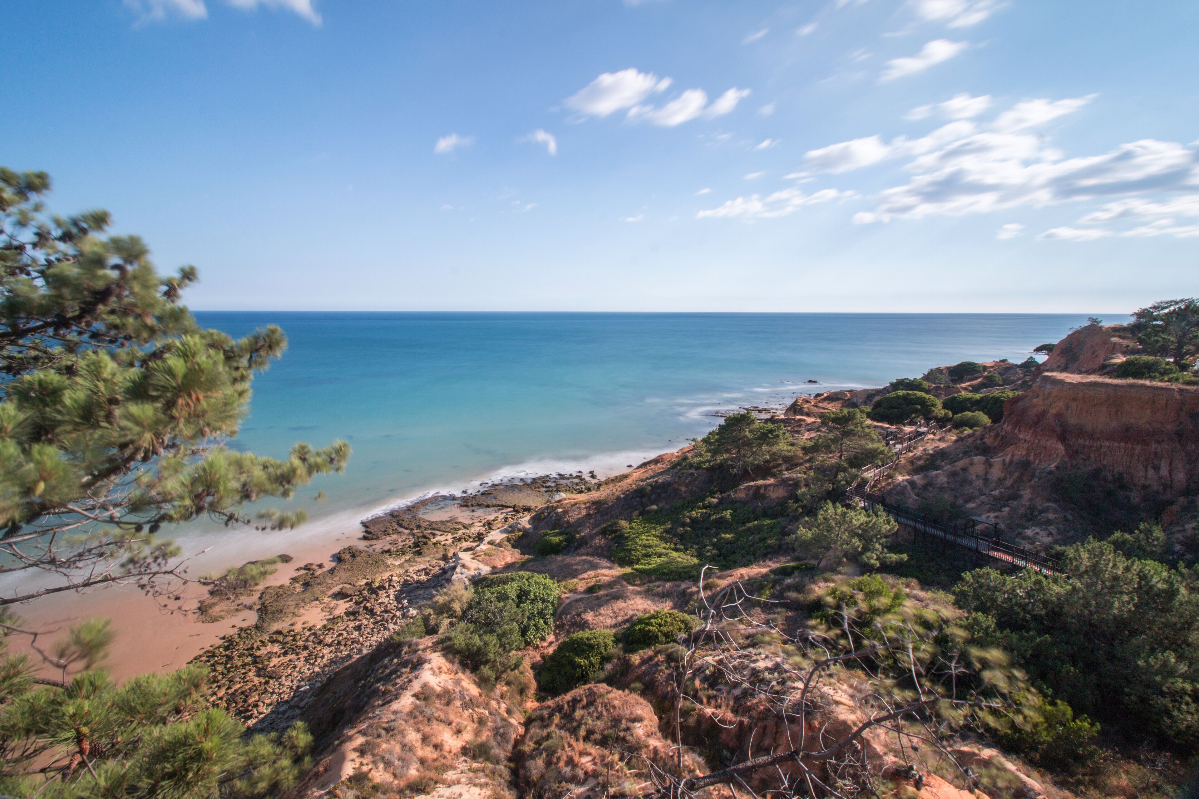 A coastal landscape with a beach, rocky cliffs, and sparse vegetation.