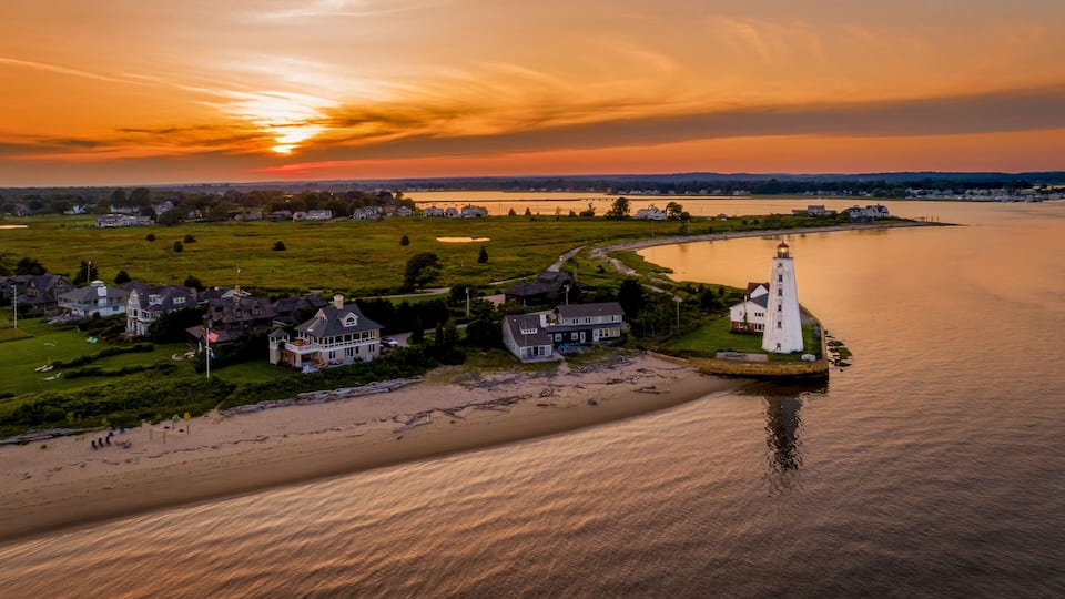A coastal town with a lighthouse, houses, and a river.