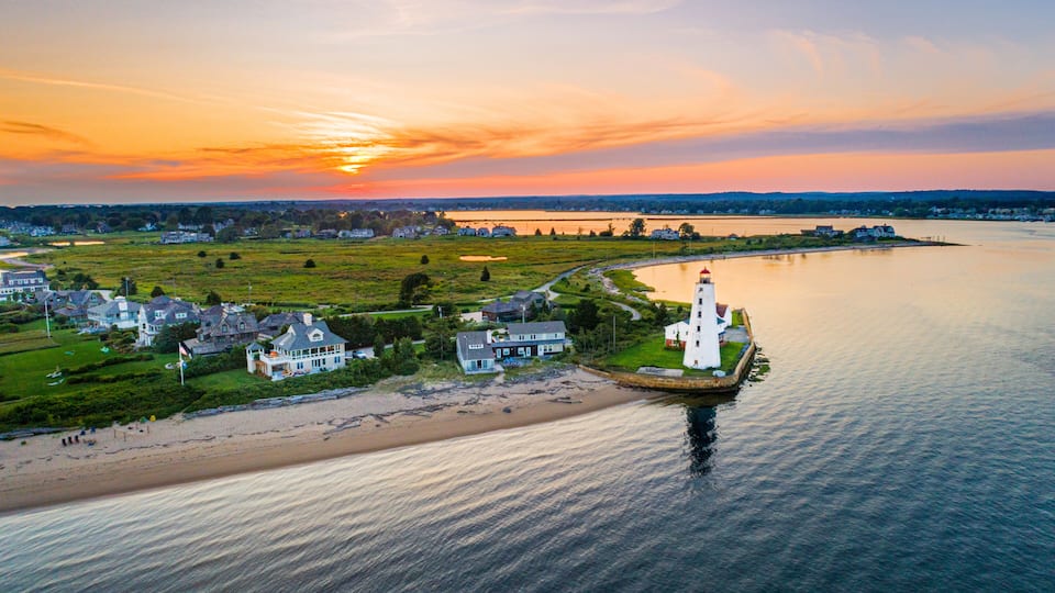 A coastal town with a lighthouse, houses, and a river.
