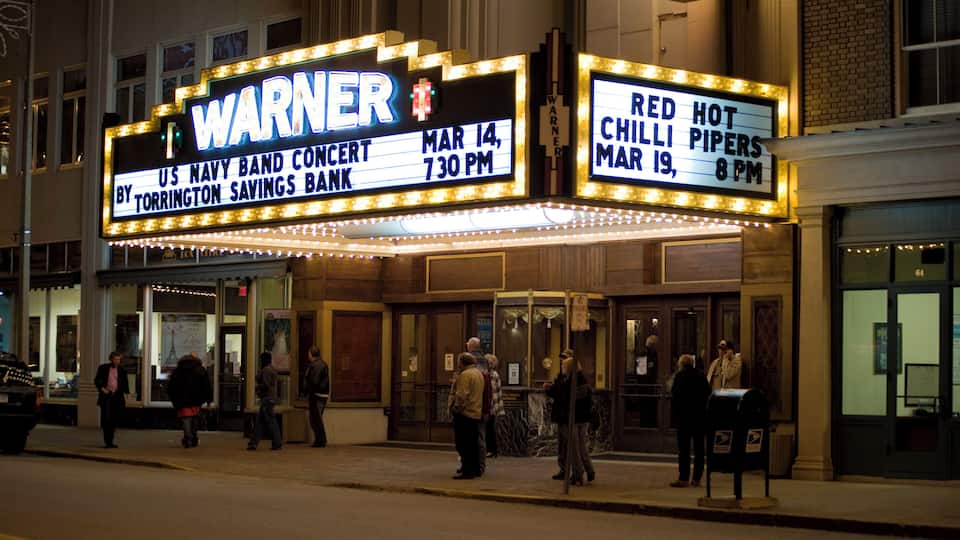 A Warner theater marquee advertising a US Navy band concert and a Red Hot Chili Peppers performance.