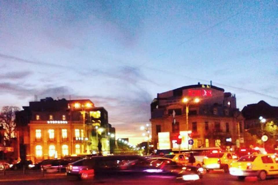 Un encreuament urbà animat amb cotxes i edificis al capvespre.