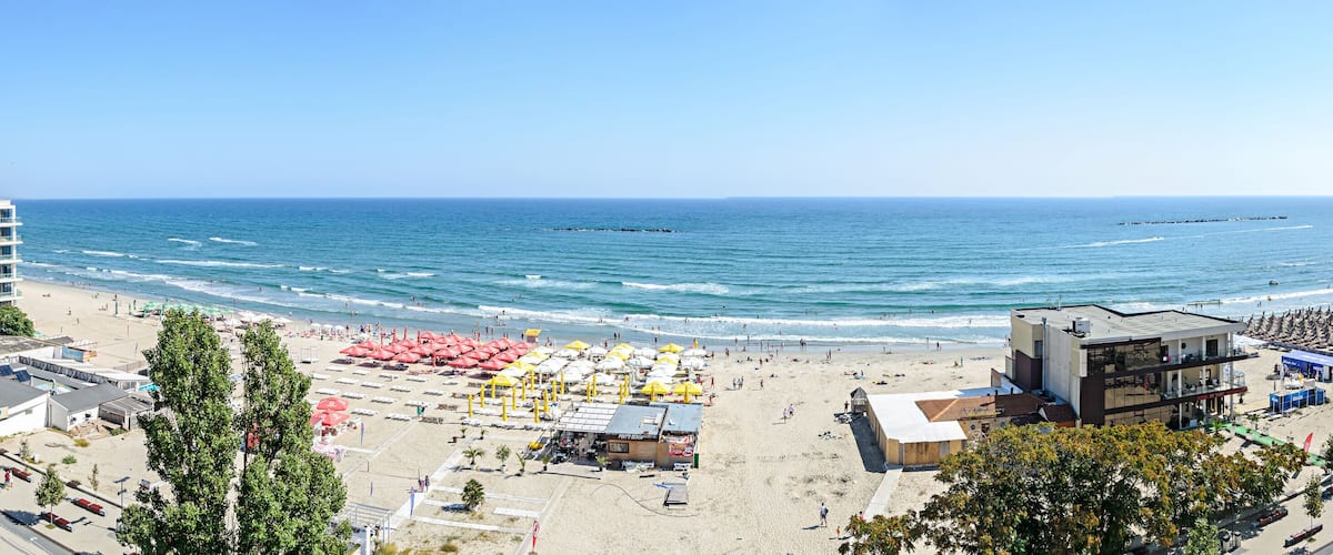 A beach with umbrellas, a building, and the ocean.