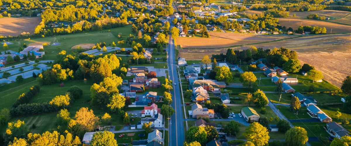 An aerial view of a suburban area with houses, roads, and green fields.