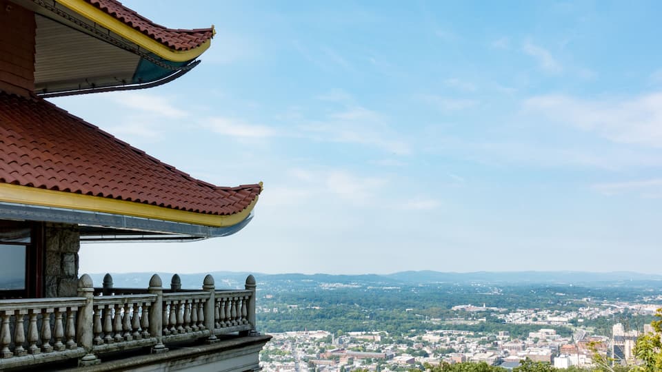 A traditional building with a red roof and a balcony overlooking a cityscape.