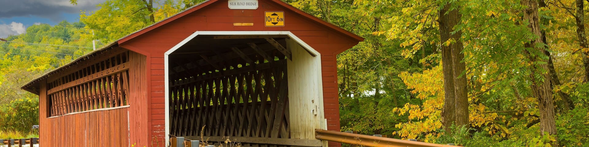Silk Road covered bridge with trees showing fall colors near Paper Mill Village, Vermont.