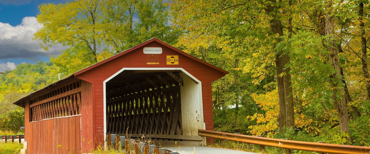 A covered bridge with a sign reading "Silk Road Bridge" and a height restriction of 10 feet 6 inches.