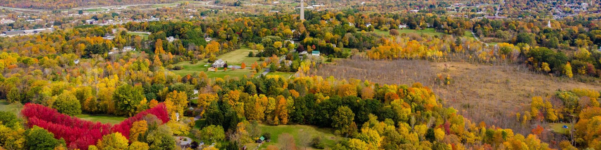 A mountainous landscape with autumn foliage, a prominent church spire, and a winding road.