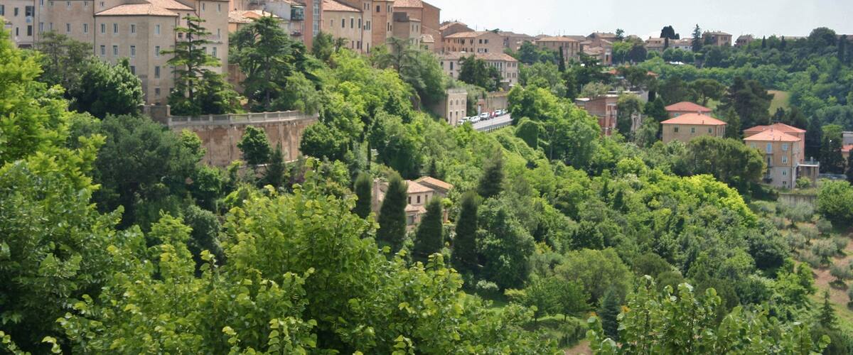 A town with historic buildings, a prominent tower, and lush greenery.