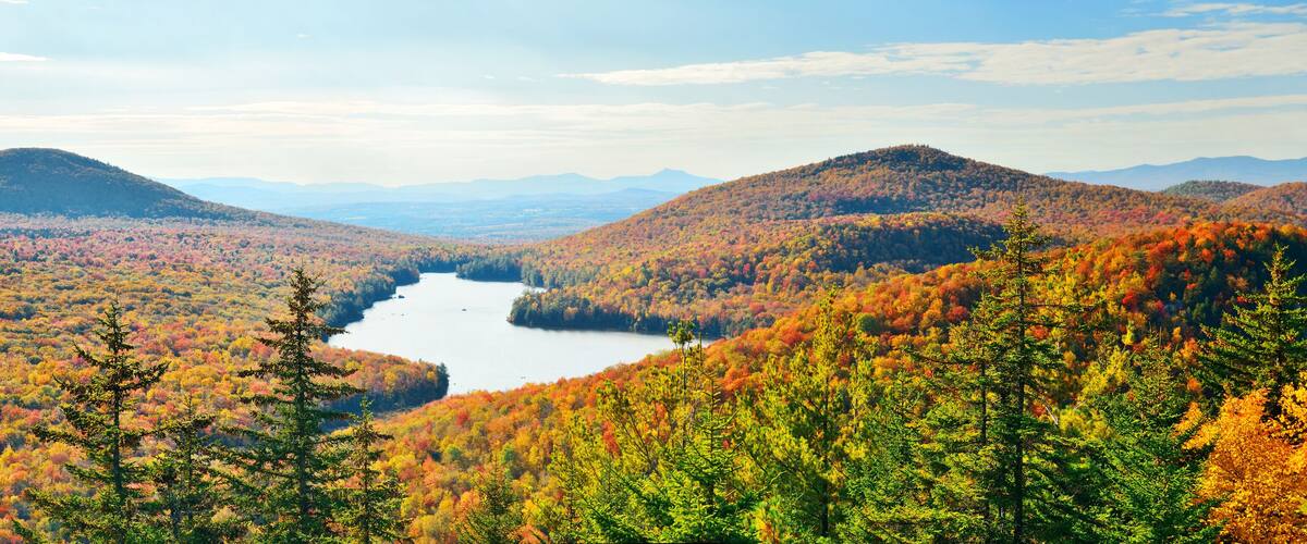 A lake surrounded by autumn-colored forests and hills.