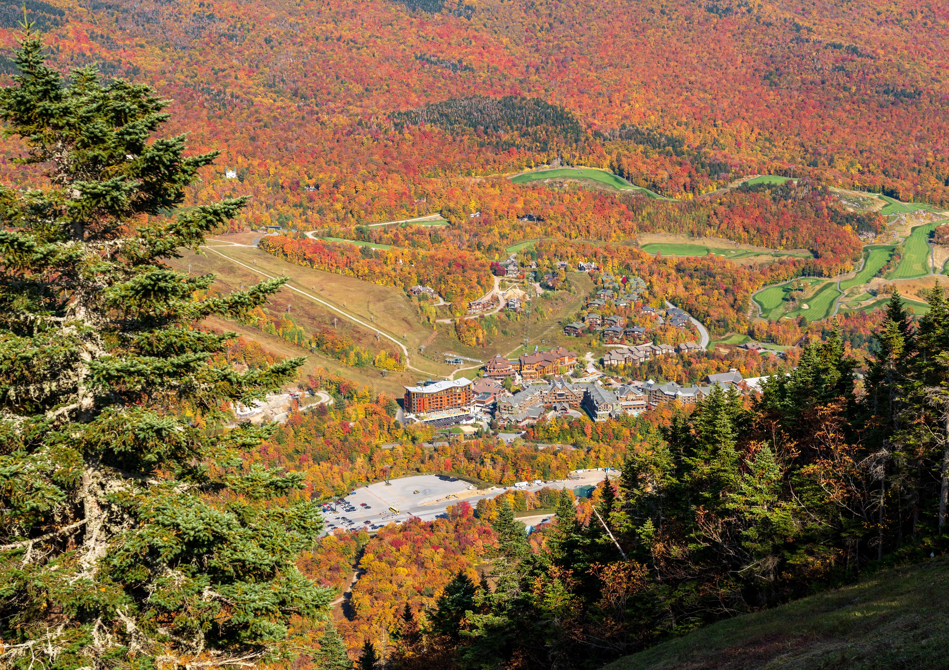 A mountainous landscape with autumn foliage, a golf course, and residential buildings.