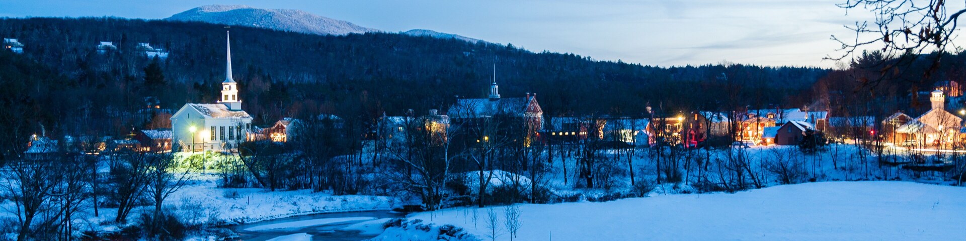 Paisaje nevado con una iglesia y un puente a lo lejos.