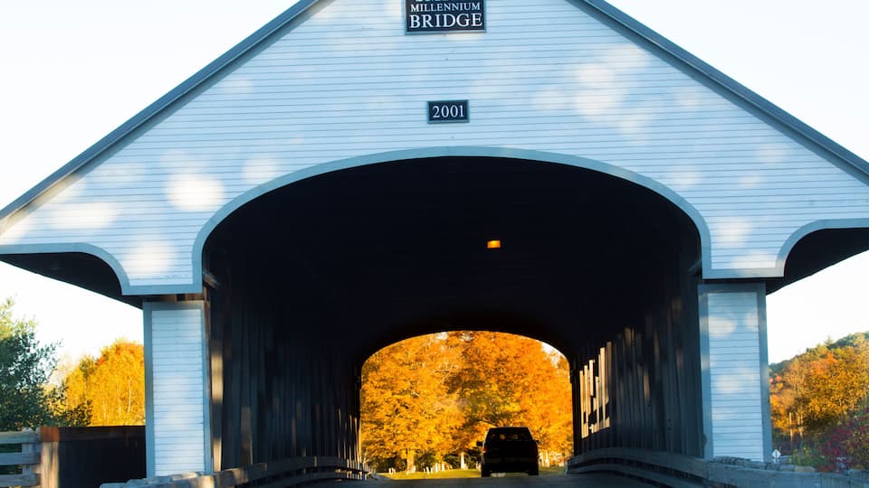 A covered bridge with a sign reading 'Smith Millennium Bridge 2001' and a car driving through it.