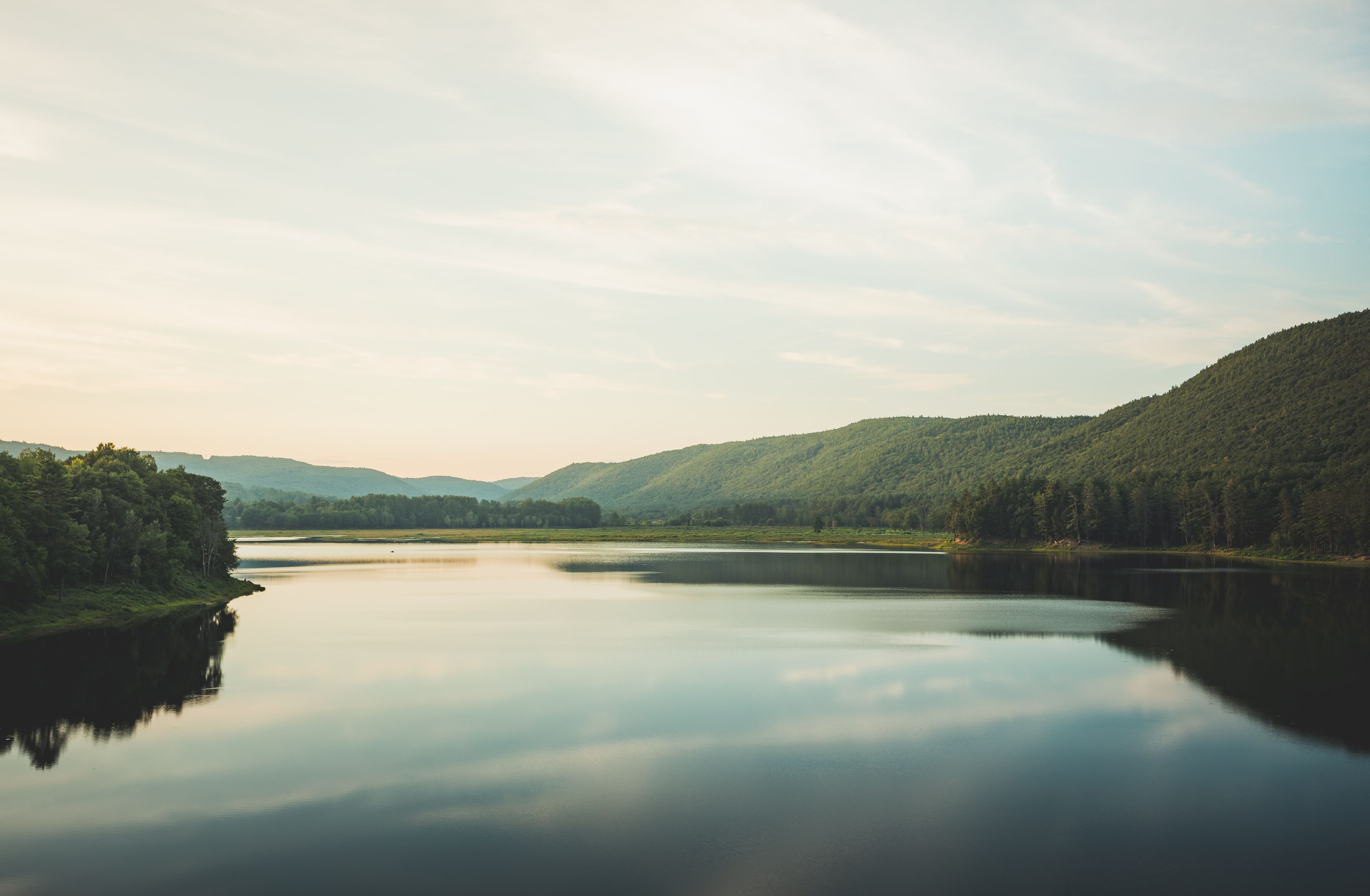 A calm lake surrounded by forested hills.